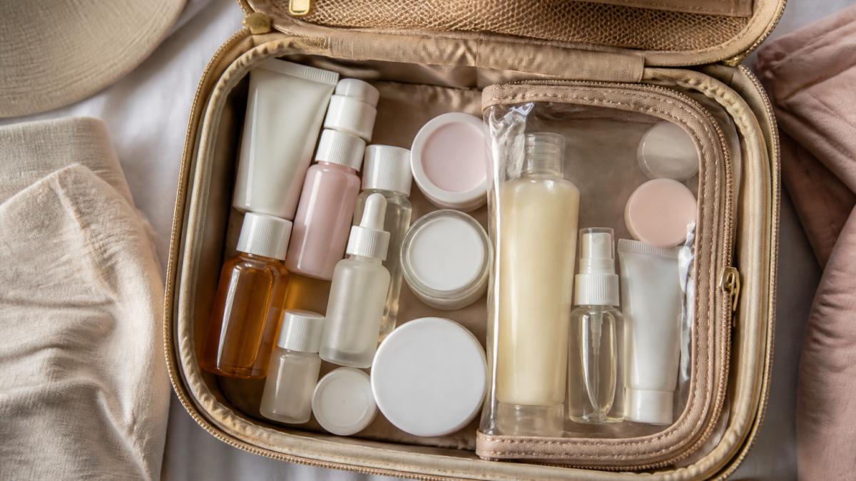 Overhead view of a neatly organized carry-on toiletry bag with travel-size skincare bottles, sealed containers, and a clear toiletry organizer pouch arranged inside, showing proper packing technique
